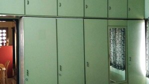 Une chambre avec une armoire verte, un miroir et une couvre-lit à motifs floraux.