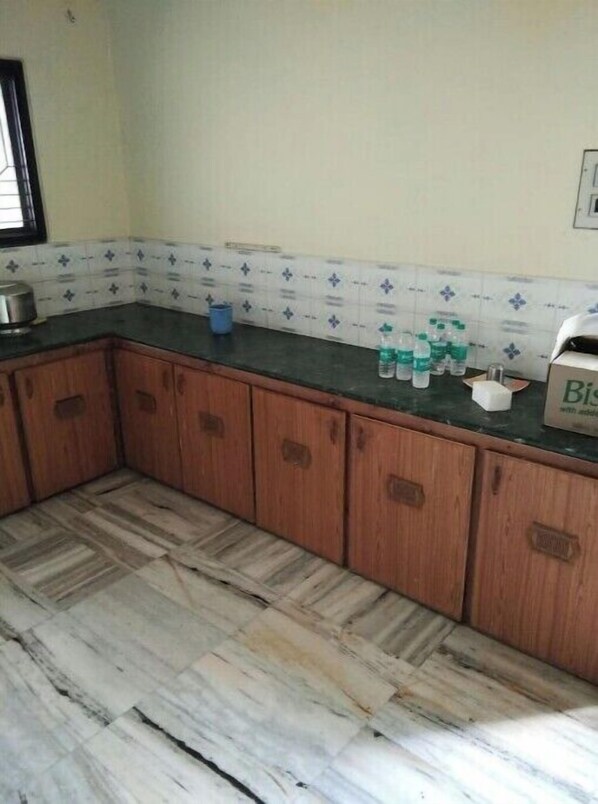 Una cocina con armarios de madera, suelo de mármol y salpicadero de azulejos.