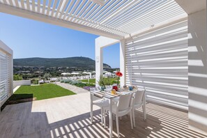 A terrace with a table set for two, overlooking a scenic landscape with hills and buildings.