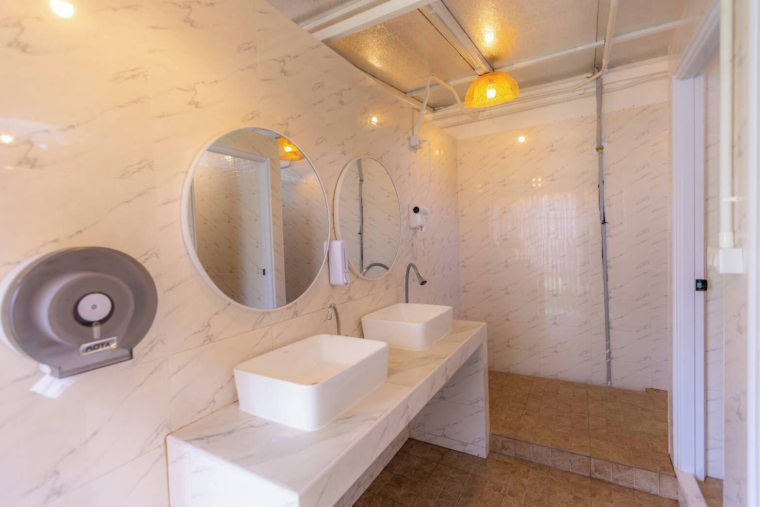 A modern bathroom with two sinks, a large mirror, and a shower area.