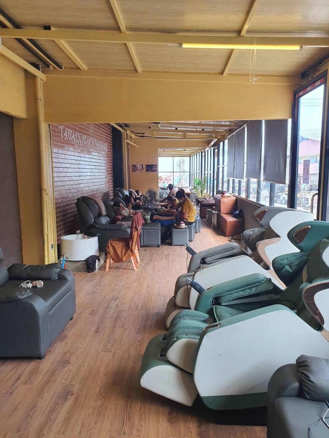 A massage parlor with multiple massage chairs, a brick wall, and large windows.