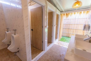 Une salle de bain moderne avec des murs en marbre, des portes en bois et un tapis vert menant à un espace extérieur.