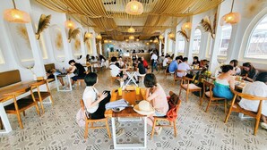 A restaurant with wooden tables and chairs, a patterned floor, and hanging lights. - Tawaen Caza Sky Camping (Koh Lan)
