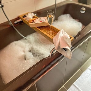 A bathtub with a wooden tray holding a glass of champagne, a bottle, and a book. - Das Lalelou- Familienurlaub Zentral in Braunlage mit Eigenem Garten (Braunlage)