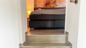 A staircase with grey tiles leading to a dark-colored sofa in a room with white walls. - Das Lalelou- Familienurlaub Zentral in Braunlage mit Eigenem Garten (Braunlage)