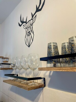 A wall with a geometric deer head decal, a wine glass rack, and decorative jars. - Das Lalelou- Familienurlaub Zentral in Braunlage mit Eigenem Garten (Braunlage)