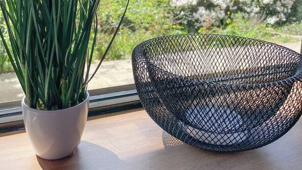 A potted plant and a wire basket on a windowsill with a view of red-roofed houses. - Das Lalelou- Familienurlaub Zentral in Braunlage mit Eigenem Garten (Braunlage)