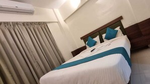 Habitación de hotel con cama, cortinas y aire acondicionado.