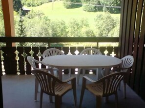 A round table with six chairs on a balcony with a view of a green landscape. - Appartement Douillet au Calmerais un Village Typique Savoyard (Châtel)