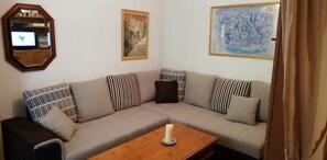 A living room with a sofa, a coffee table, a mirror, and two framed pictures on the wall. - Appartement Douillet au Calmerais un Village Typique Savoyard (Châtel)