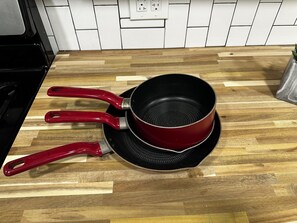 Uma cozinha com bancada de madeira, uma panela vermelha e uma tampa combinando.