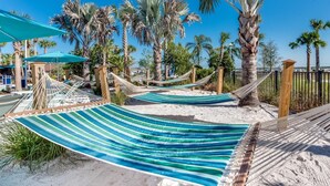 A hammock setup on a sandy beach with palm trees and a clear blue sky. - Paradise Point at Windsor Island Resort Orlando by Shine Villas (Davenport)