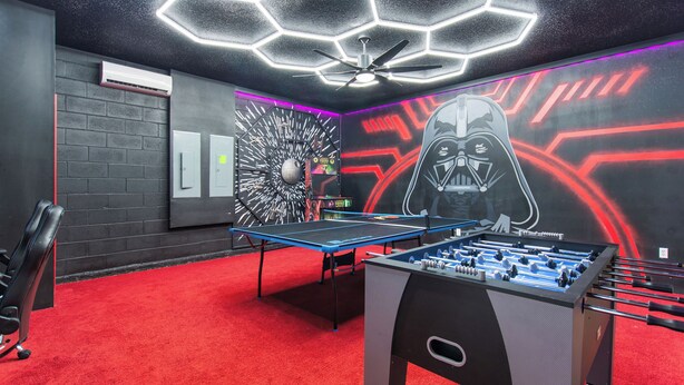 A room with a foosball table, a ceiling fan, and a wall with a Darth Vader mural. - Paradise Point at Windsor Island Resort Orlando by Shine Villas (Davenport)