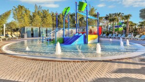A water play area with slides and fountains, surrounded by palm trees and lounge chairs. - Paradise Point at Windsor Island Resort Orlando by Shine Villas (Davenport)