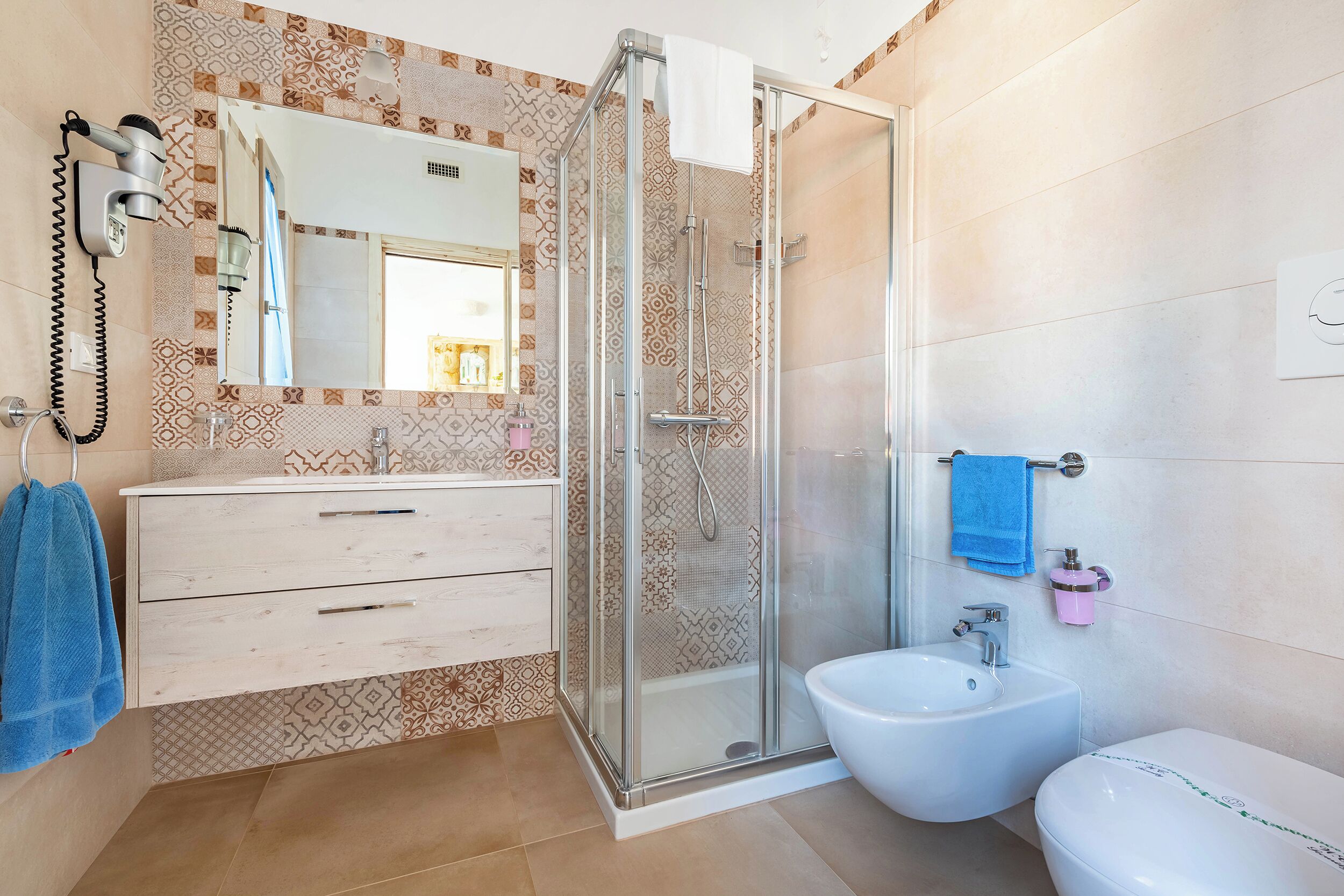 A bathroom with a glass-enclosed shower, a sink, and a toilet.