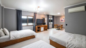 Habitación de hotel con dos camas, un escritorio con televisor, un refrigerador pequeño y un comedor.