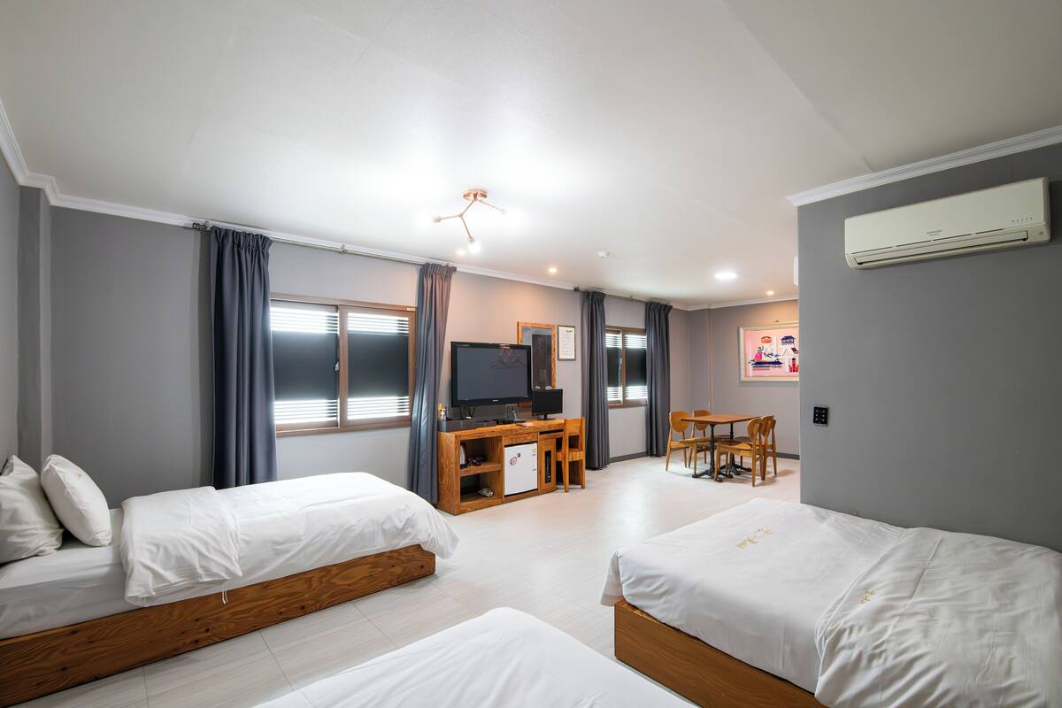 Une chambre d’hôtel avec deux lits, un bureau avec une télévision, un petit réfrigérateur et un coin repas.