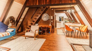 Une chambre mansardée chaleureuse, avec un lit, une chaise, un bureau et un coin repas équipé de chaises.