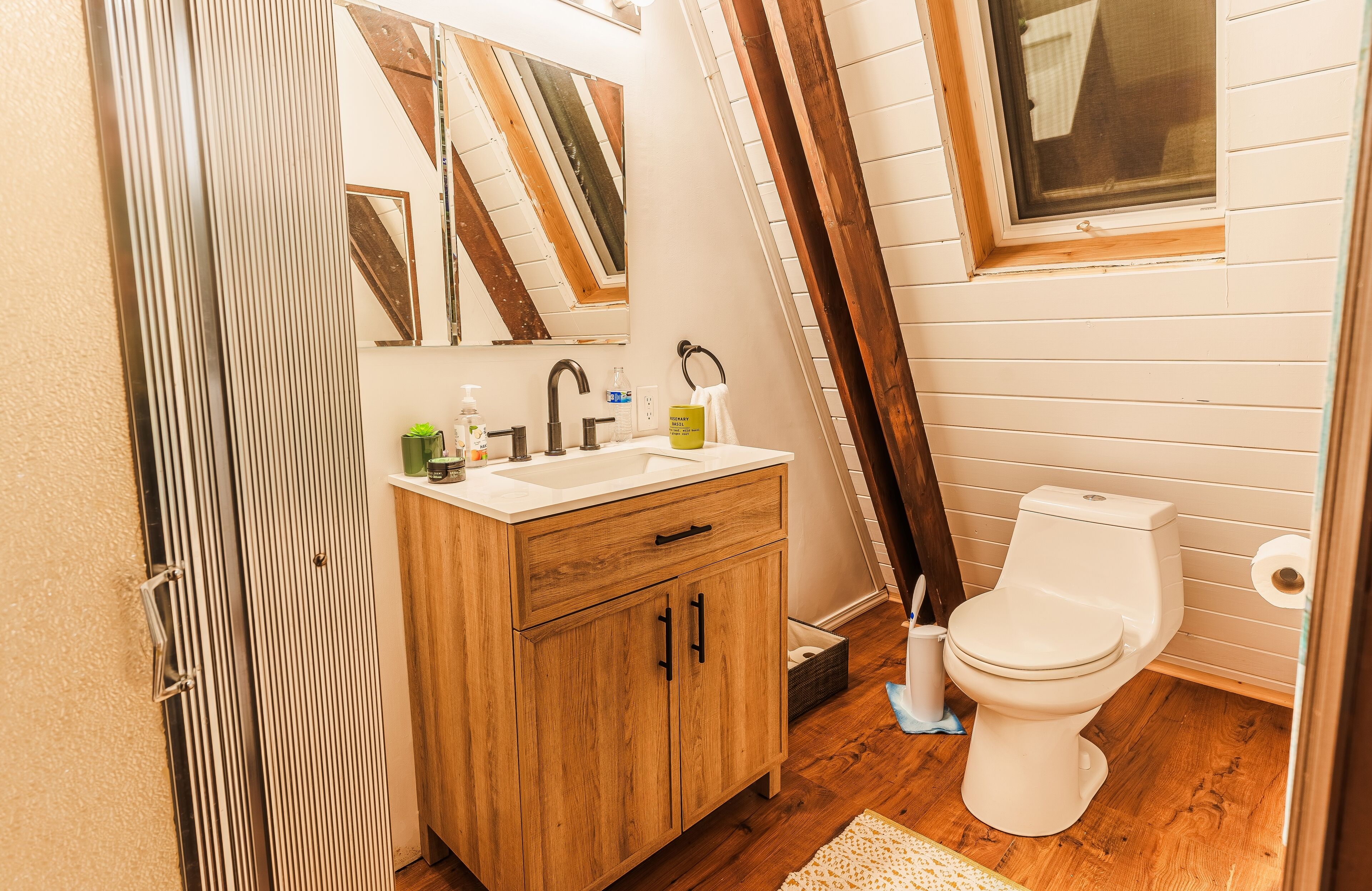 A bathroom with a wooden vanity, a sink, a mirror, and a toilet.