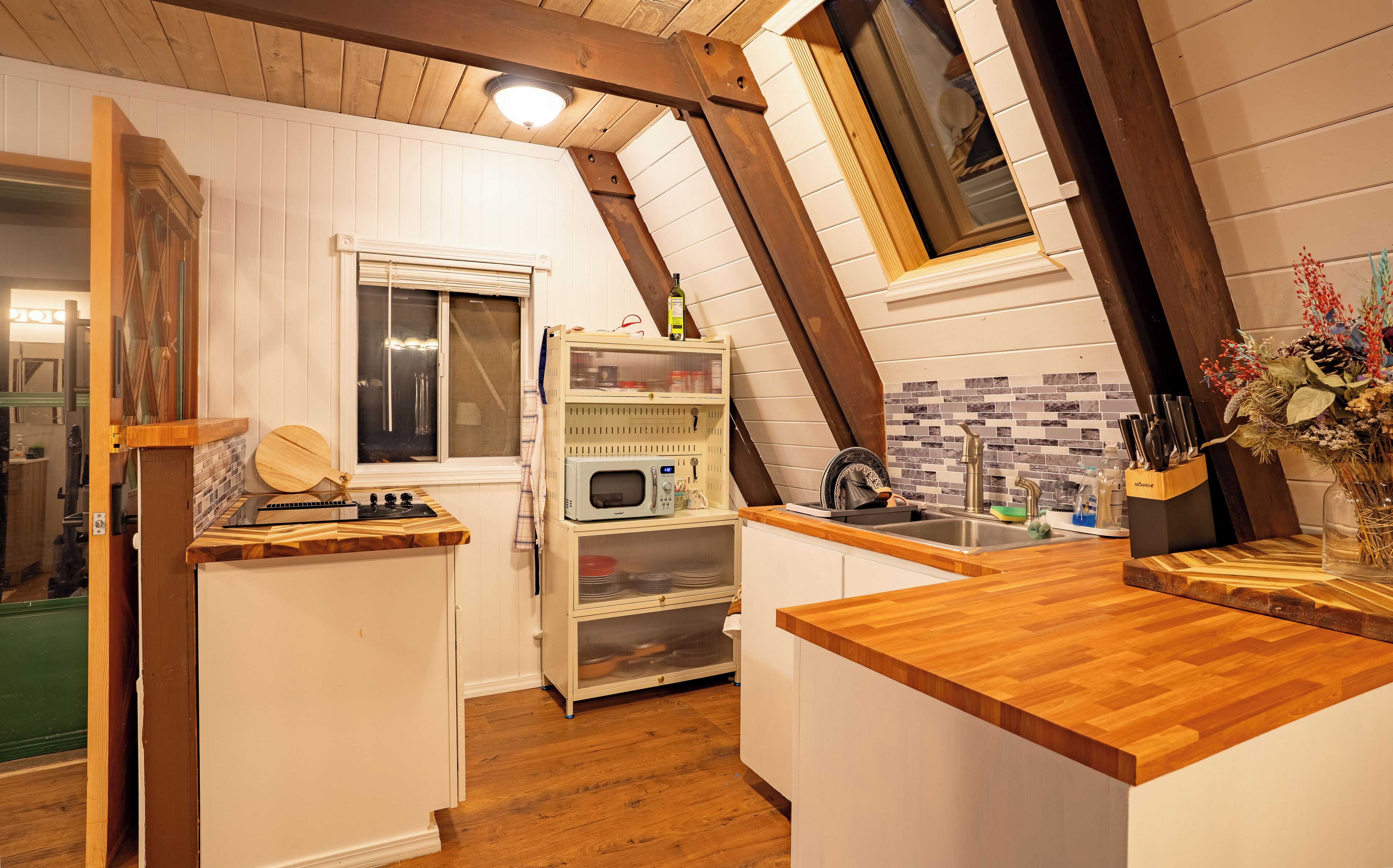 A compact kitchen with wooden countertops, a built-in microwave, and a window above the sink.