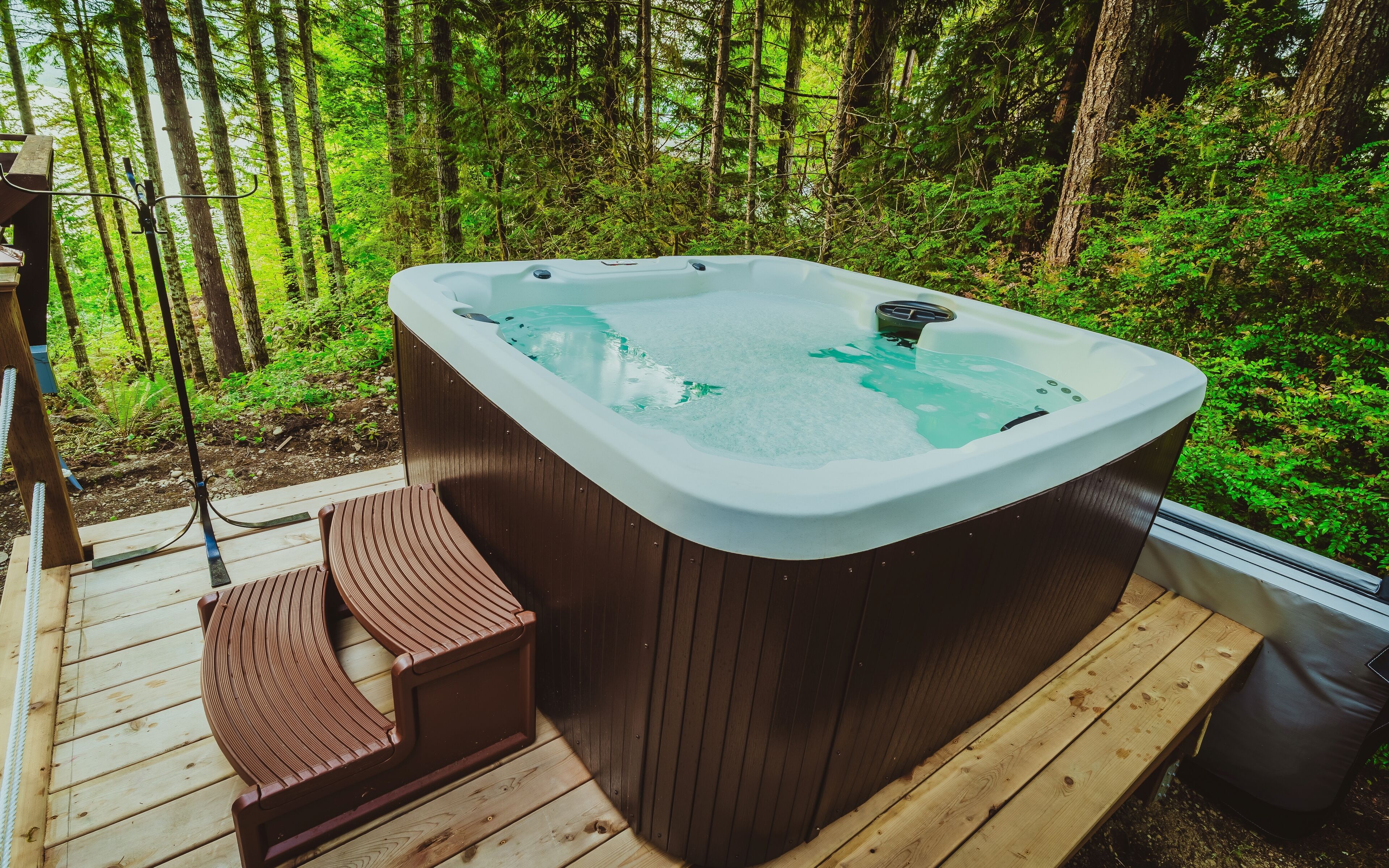 Ein Whirlpool auf einer Holterrasse, umgeben von einem Wald.
