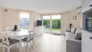 Ein modernes Wohnzimmer mit Essbereich, einer Couch und einem Fernseher.