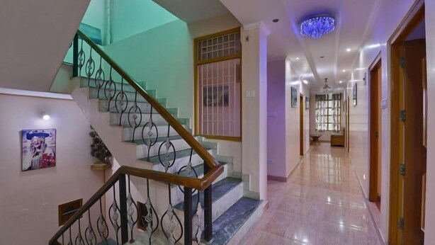 Un pasillo de hotel con una escalera de mármol, un candelabro y una puerta a la derecha.