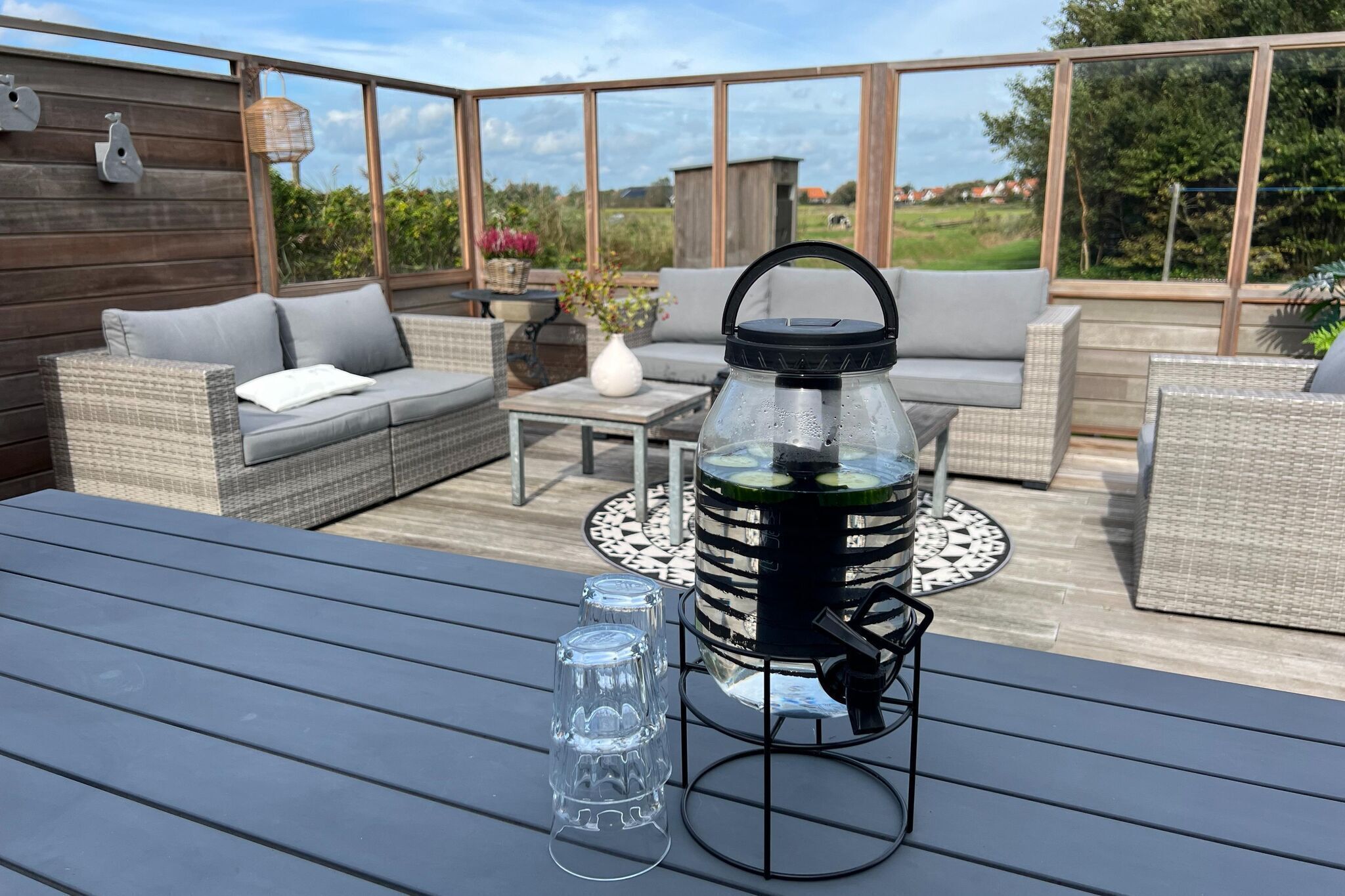An outdoor patio with wicker furniture, a table, and a water dispenser.