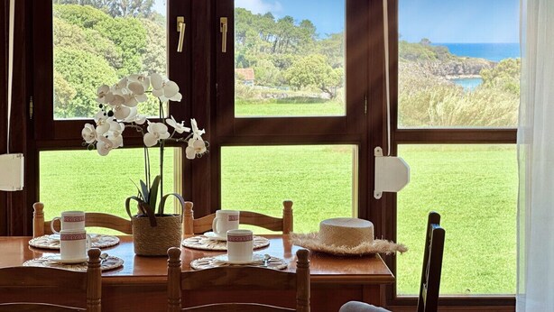 Une table à manger décorée avec des fleurs d’orchidée blanches, un gâteau et deux tasses blanches.