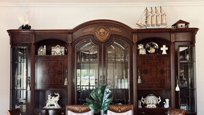 Un comedor con un armario de madera, sillas y una mesa.