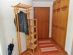 Un pasillo con un tendedero de madera, una puerta y un armario.