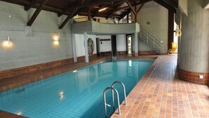 Una piscina interior amb terra de rajola i escales metàl·liques.