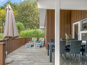 A covered outdoor area with a wooden deck, lounge chairs, a table, and chairs. - "Maira" -  from the sea by Interhome (Hadsund)