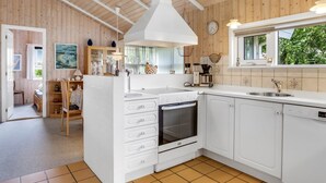 Une cuisine moderne avec des meubles blancs, un four Bosch et une fenêtre donnant sur un espace verdoyant.