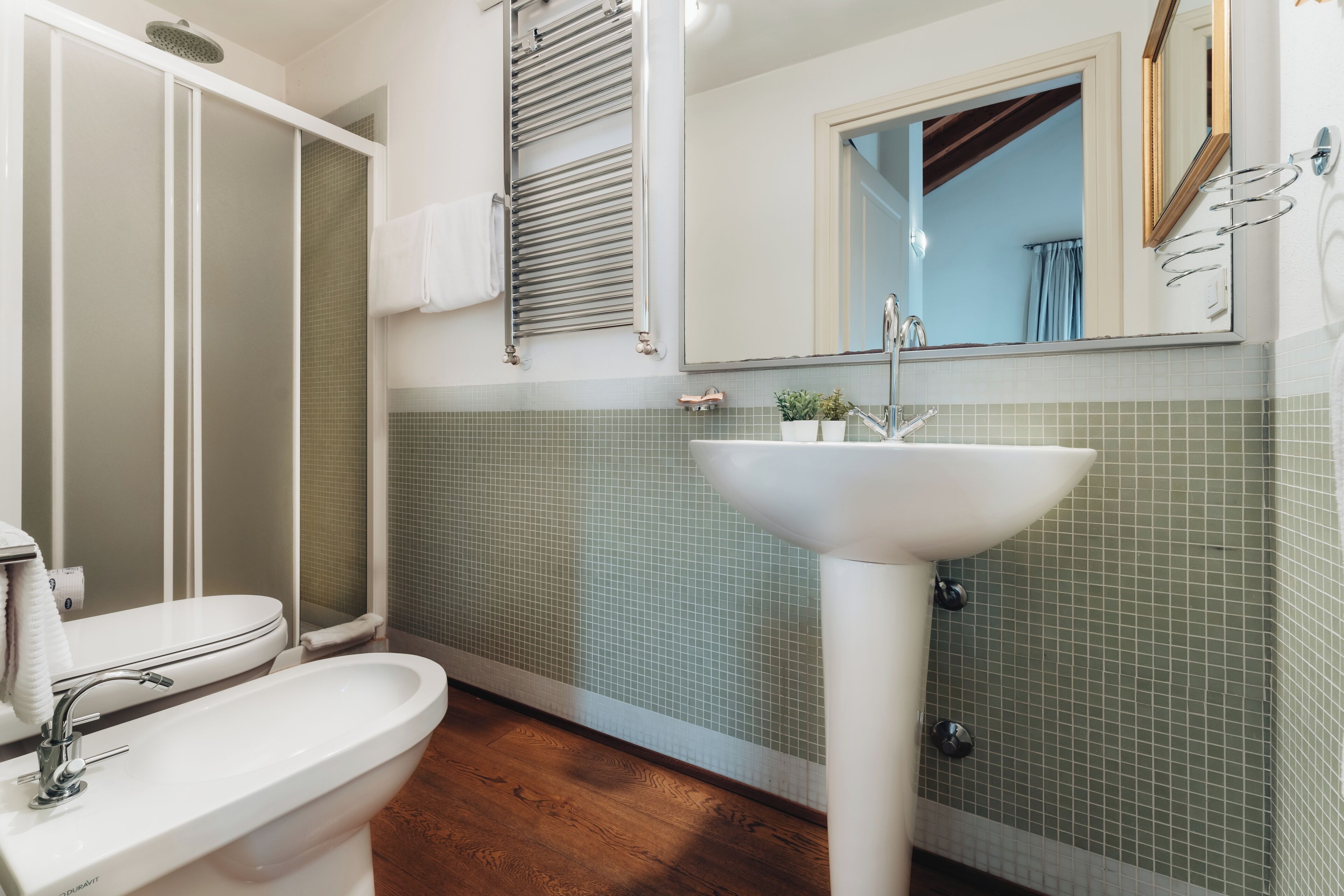 A bathroom with a white sink, a mirror, and a shower with a glass door.