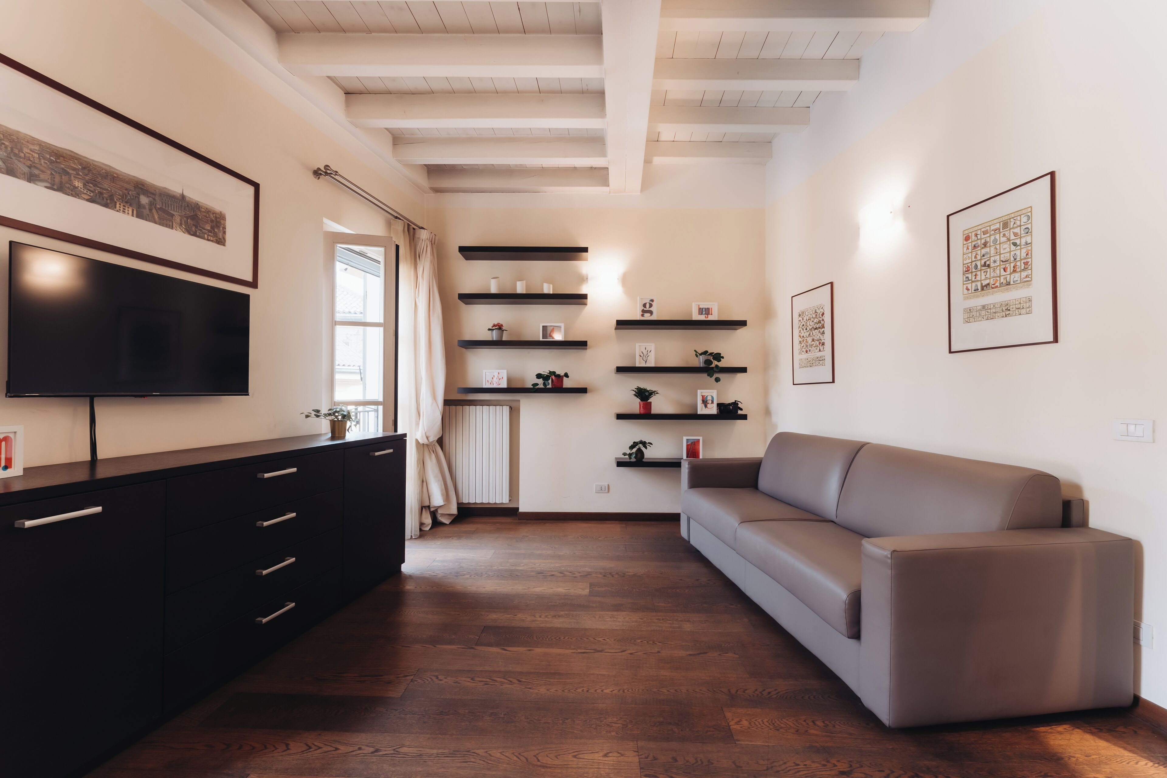 A modern living room with a sofa, TV, and built-in shelves.