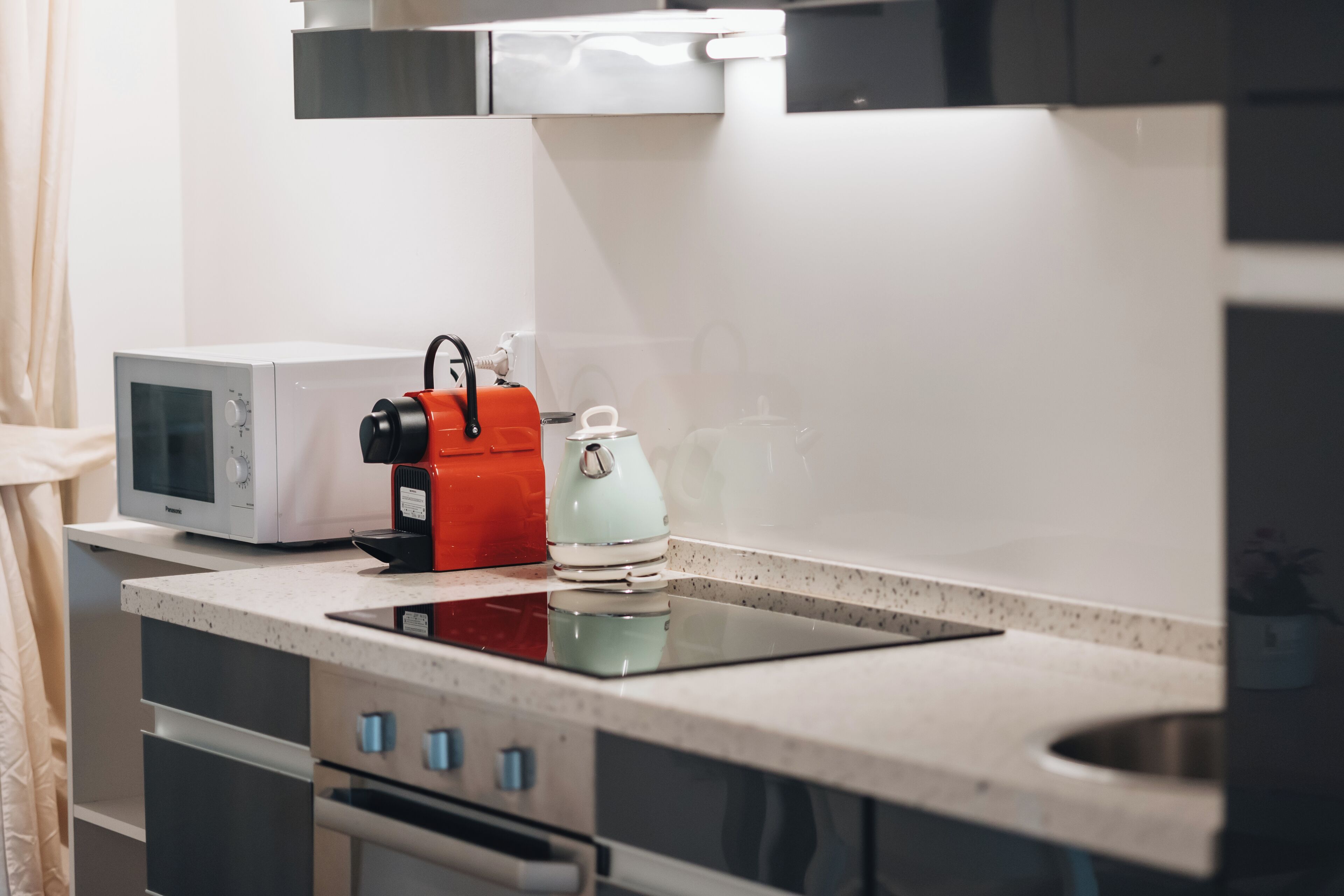A kitchen with a microwave, kettle, and toaster on the countertop.