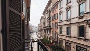 A narrow street with buildings on either side, featuring balconies and storefronts. - La dimora di Brera (Milan)