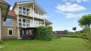 A two-story house with a balcony, a covered patio, and a well-maintained lawn.