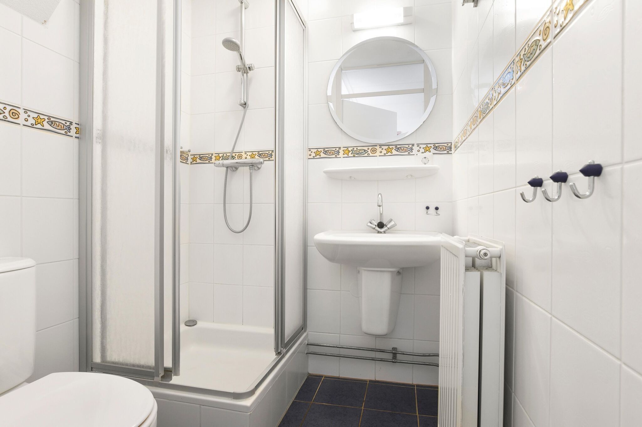Ein Badezimmer mit Dusche, Toilette, Waschbecken und Spiegel.