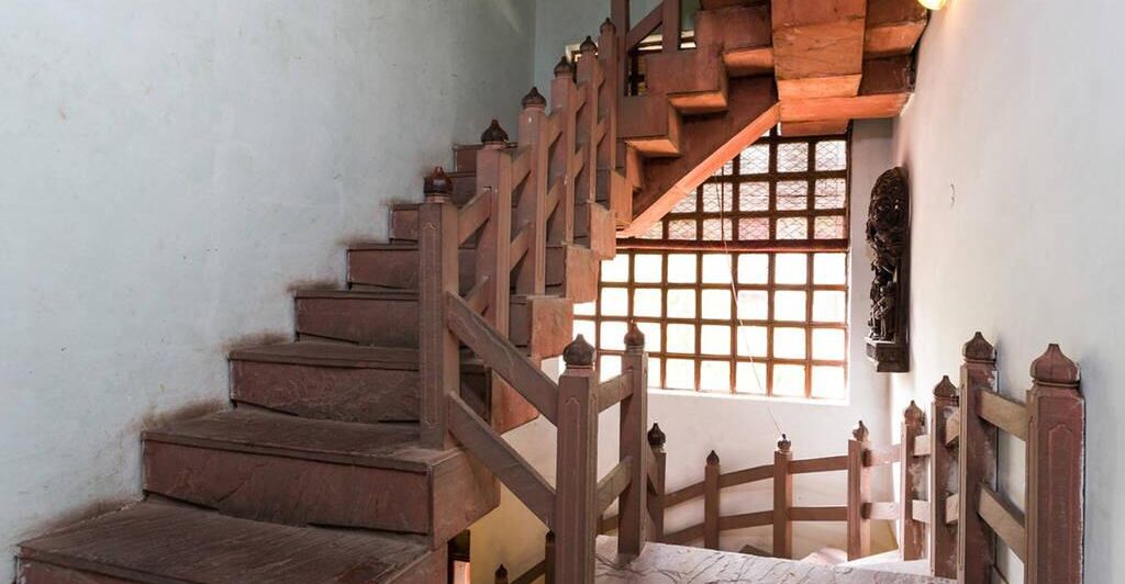 A wooden staircase with a handrail and a window with a grid pattern.
