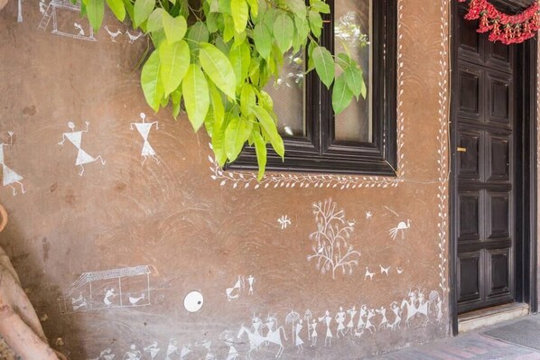 A building facade with a window and a door, decorated with white wall art depicting various figures and scenes.