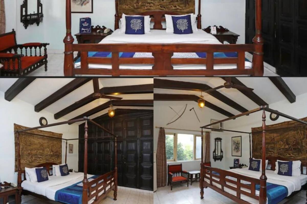 Una cama con dosel, una silla de madera, una mesita y un reloj en la pared.
