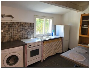 A compact kitchen with a washing machine, a stove, a sink, and a window with a view. - Apartment in villa on shady plot, near Bastia town center, parking. (Ville-di-Pietrabugno)