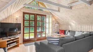 A modern loft-style room with a large gray sectional sofa, a flat-screen TV, and a sliding glass door leading to a balcony. - "Niesina" - 600m to the fjord by Interhome (Højslev)