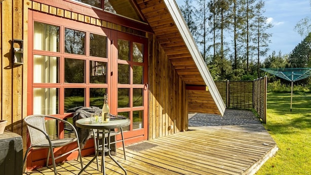 A wooden cabin with a covered patio, a table with chairs, and a view of the surrounding forest. - "Niesina" - 600m to the fjord by Interhome (Højslev)