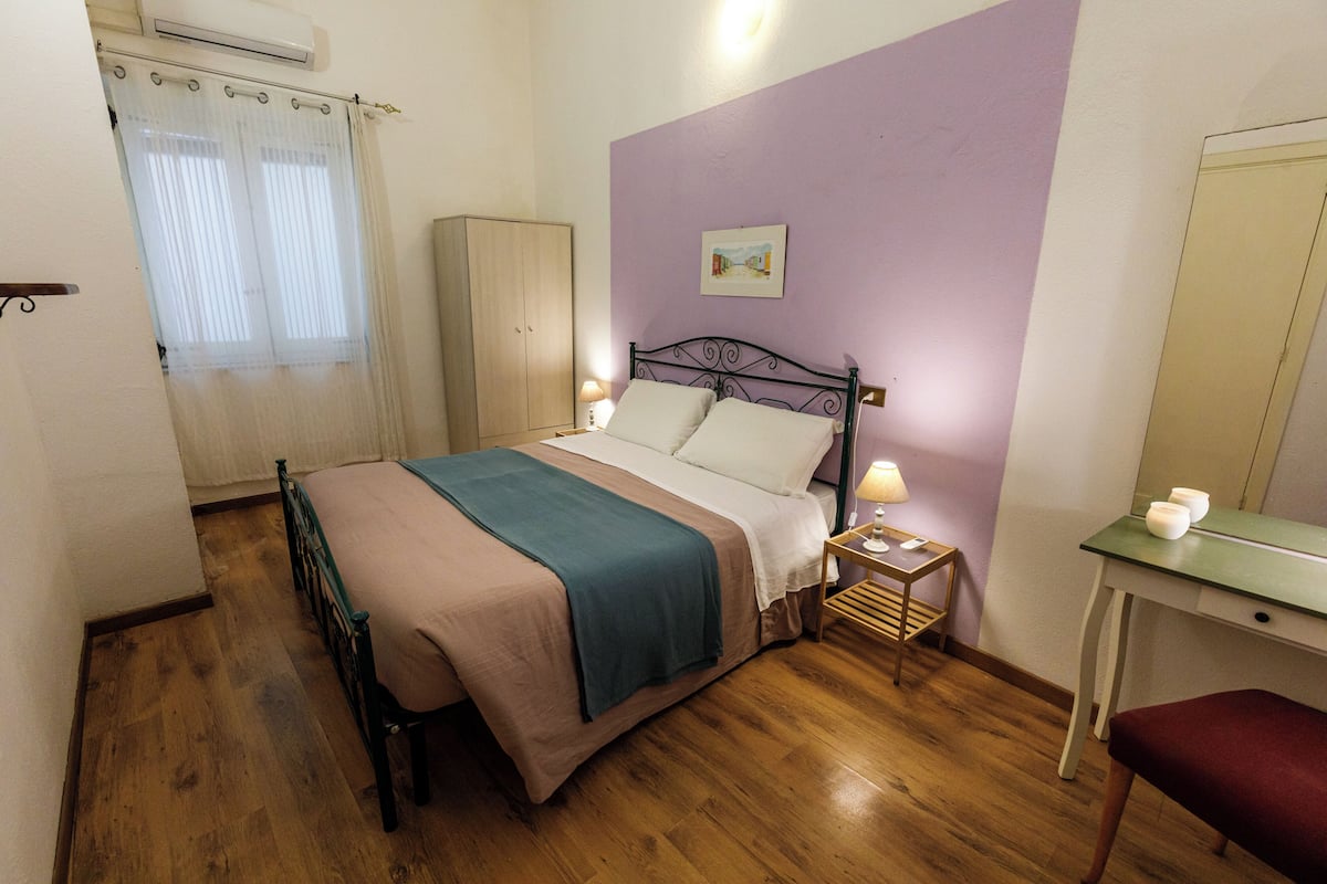Une chambre à coucher comprenant un lit, un bureau, une chaise, une armoire et une fenêtre avec des rideaux.