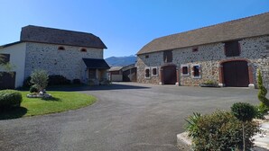 A stone building with a paved driveway and a small lawn area. - House with swimming pool and bowling green at the foot of the Pyrenees (Asson)