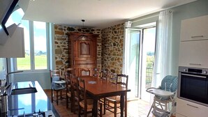 A kitchen with a dining table, chairs, a stove, and a built-in oven. - House with swimming pool and bowling green at the foot of the Pyrenees (Asson)