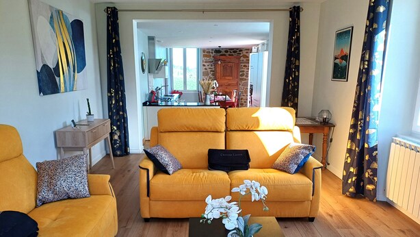 A living room with a yellow sofa, a coffee table with a plant, and a view into the kitchen. - House with swimming pool and bowling green at the foot of the Pyrenees (Asson)